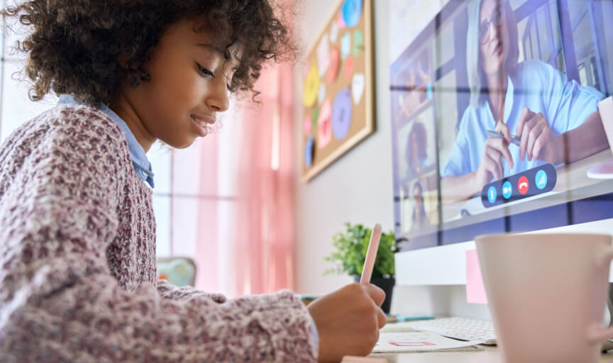A young female student sits at her desk at home, engaging in a remote learning session.