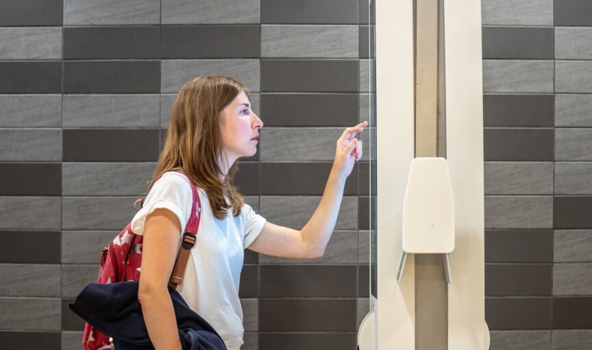 A customer concentrates as they use a large touchscreen display to make a purchase in-store, to illustrate the concept of customer efforts score