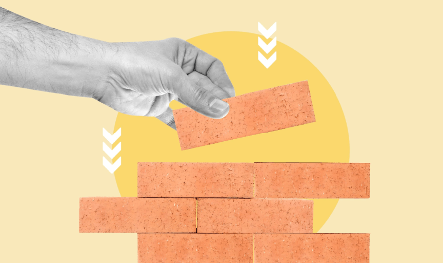 Image of a hand either adding or taking away a brick from a wall, to illustrate the concept of employee retention